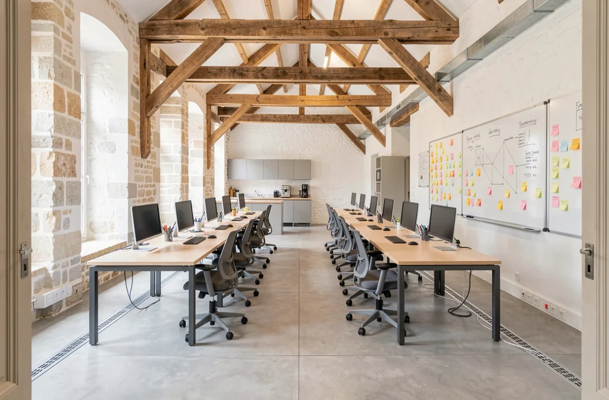 Vue intérieure d'un espace de coworking vide dans un bâtiment historique rénové à Arras avec poutres en bois et mobilier moderne